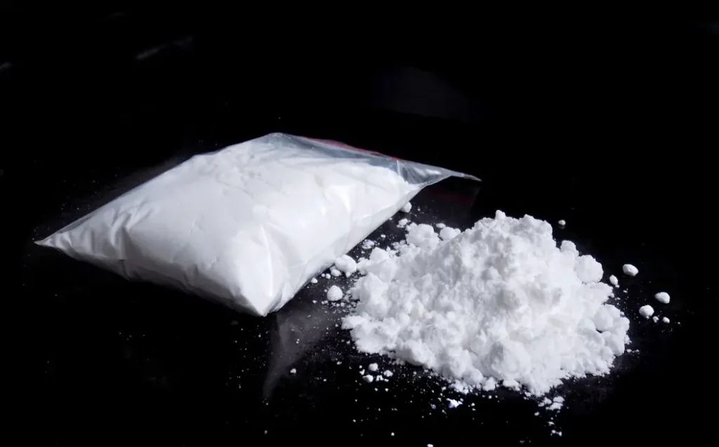 Cocaine drug powder in bag and cocaine powder pile.